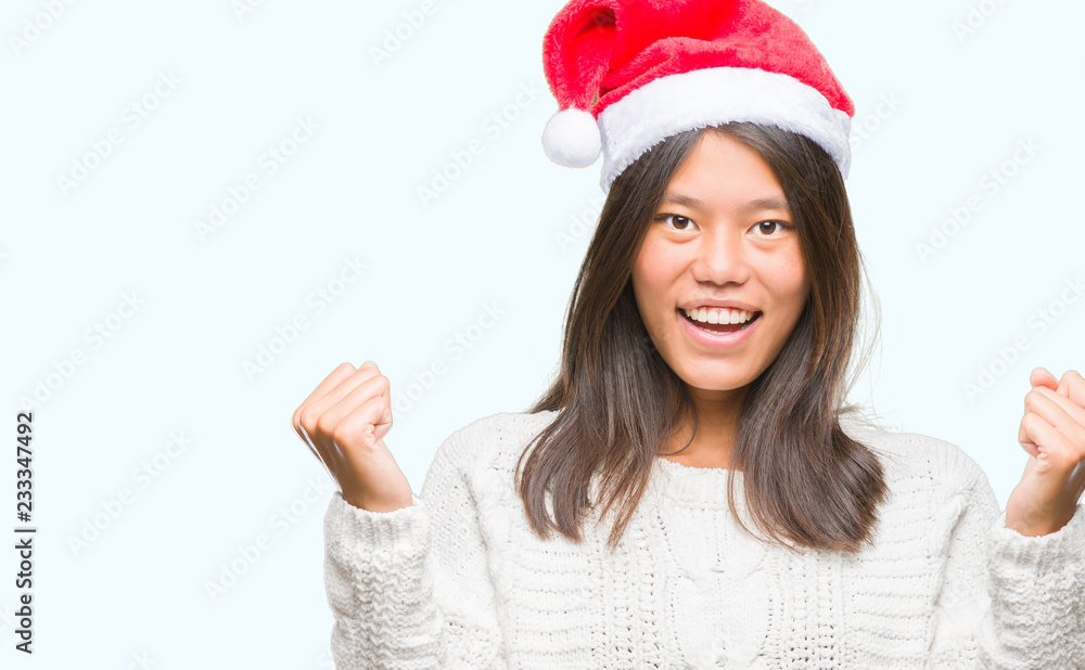 Young asian woman wearing christmas hat over isolated background celebrating surprised and amazed for success with arms raised and open eyes. Winner concept. Young asian woman wearing christmas hat over isolated background celebrating surprised and amazed for success with arms raised and open eyes. Winner concept.