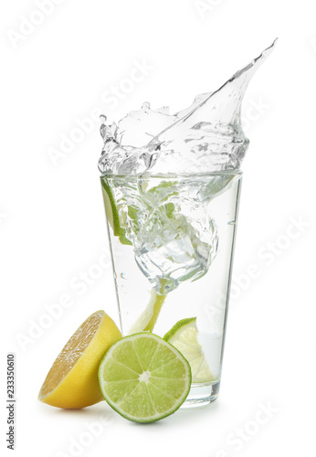 Glass of water with lemon, lime and mint on white background