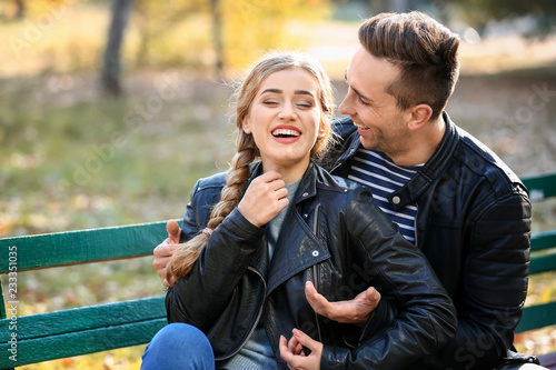 Loving young couple sitting on wooden bench in autumn park © Pixel-Shot