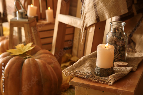 Burning candle on wooden table in room