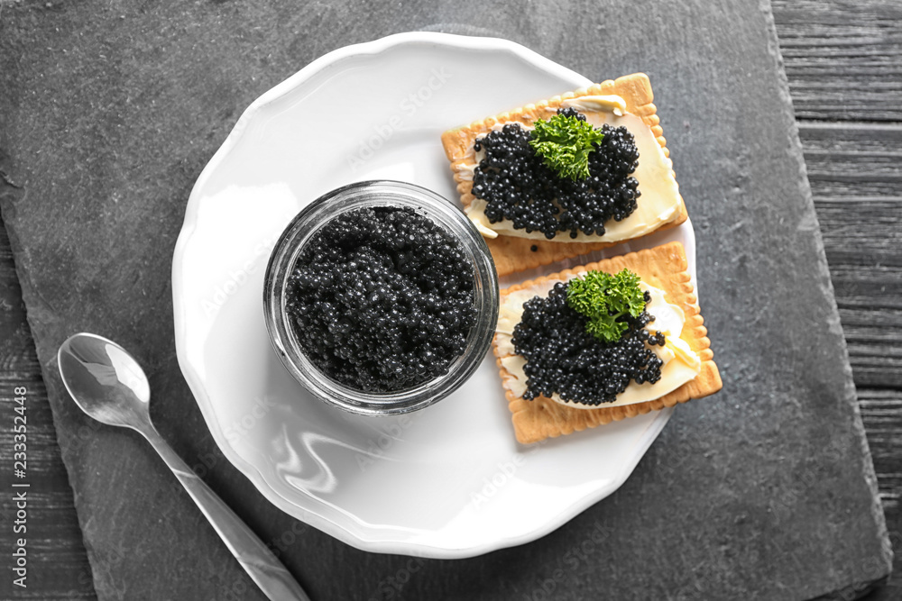 Jar and cookies with delicious black caviar on plate Jar and cookies with delicious black caviar on plate