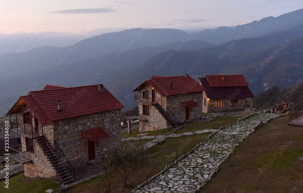 Stone houses with red roofs on the hillside at dawn in Armenia against the sky