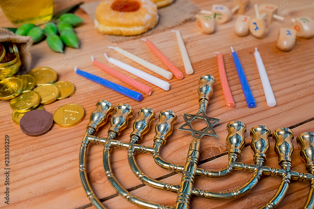 Top view of jewish holiday hanukkah celebration with menorah (traditional candelabra), wooden dreidels (spinning top), donut, olive oil and chocolate coins on wooden table.