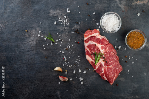 Raw beef steak with spices on black background. Flat lay.Top view