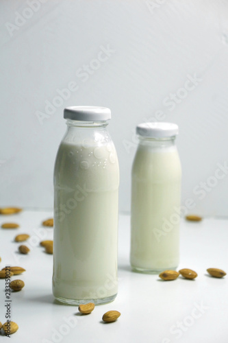 Almond milk with almond on a white table. Plant based milk