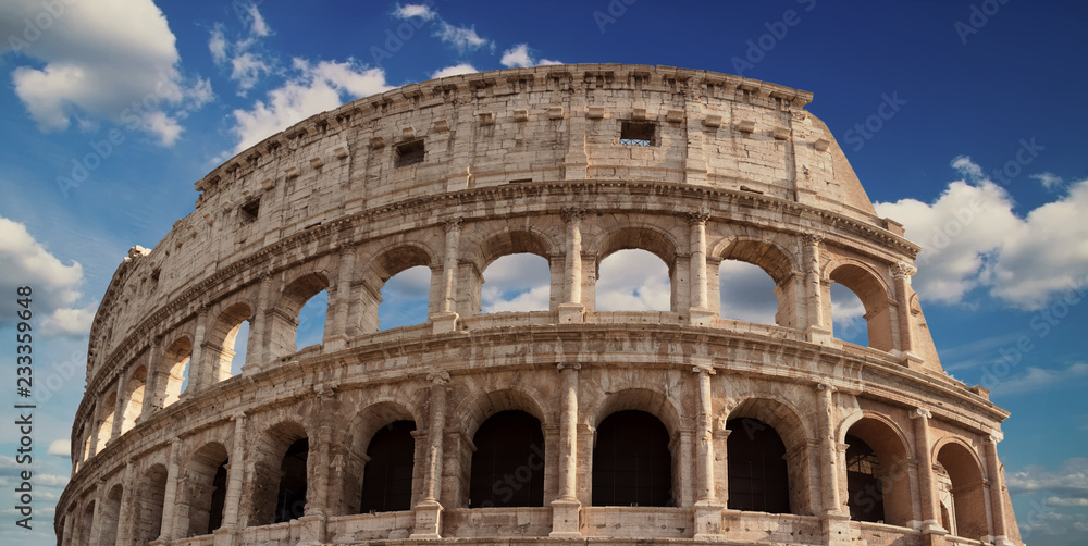 Detail of the arches of the Colosseum. Marble ruins over a blue sky