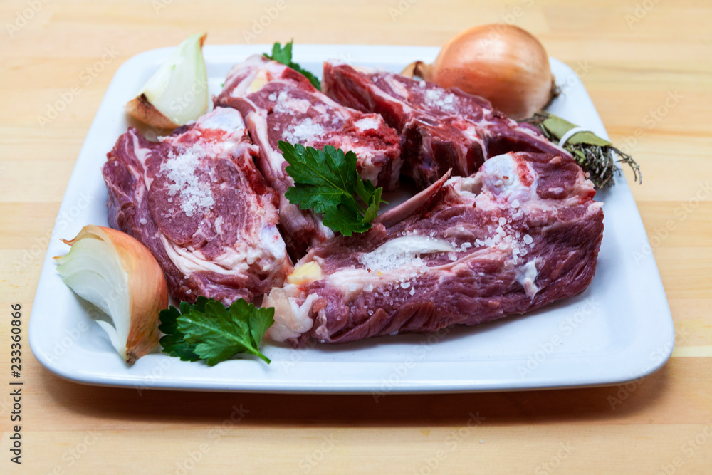 Pieces of fresh lamb on the plate . Delicious fat-tailed lamb with onion on the plate . Meat to be grilled.