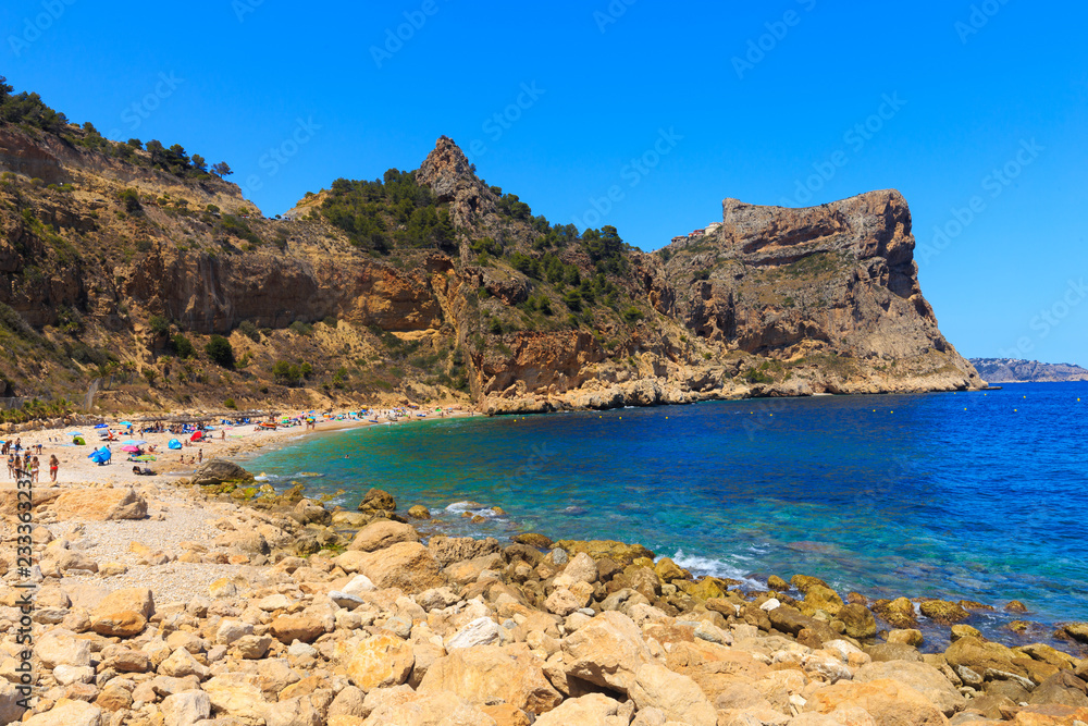 Beautiful view of beach in a bay with turquoise water in the sun, La playa Moraig in Cumbre del Sol, Spain.