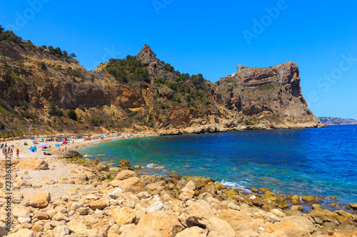 Beautiful view of beach in a bay with turquoise water in the sun, La playa Moraig in Cumbre del Sol, Spain.