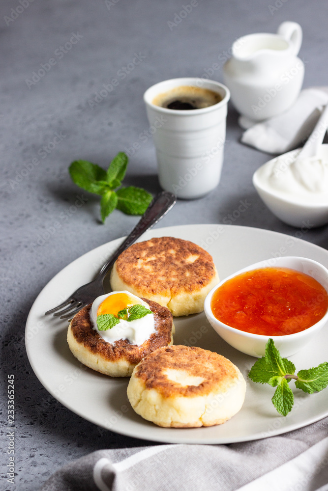 Cottage cheese pancakes or fritters with jam, natural yogurt or sour cream and mint. Traditional Ukrainian and Russian cuisine. Syrniki. Healthy and diet breakfast.