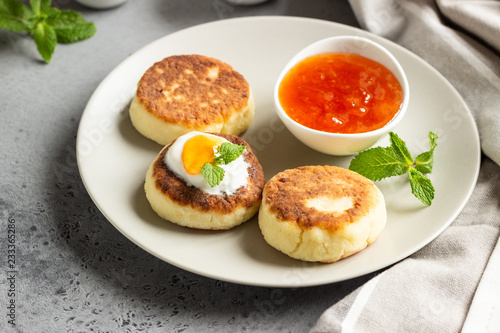 Cottage cheese pancakes or fritters with jam, natural yogurt or sour cream and mint. Traditional Ukrainian and Russian cuisine. Syrniki. Healthy and diet breakfast.