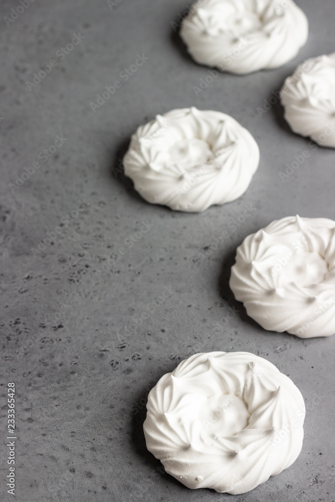 Mini Pavlova or meringue nests, selective focus. Grey concrete background. Copy space. Mini Pavlova or meringue nests, selective focus. Grey concrete background. Copy space.
