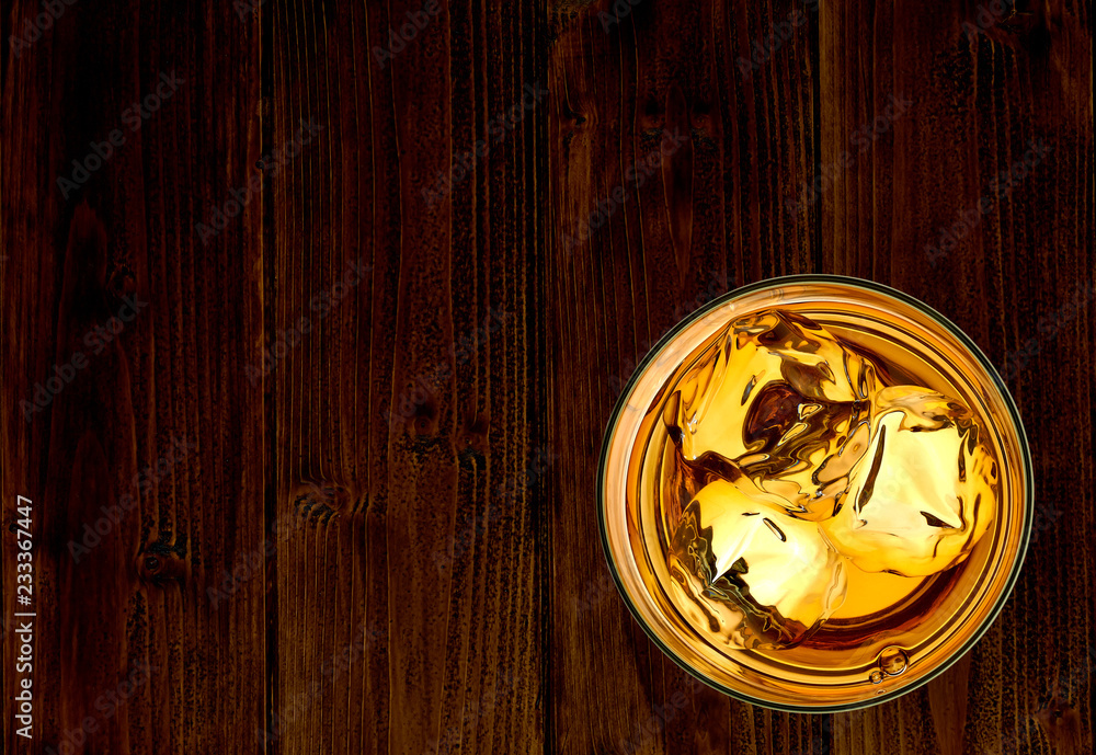 Whiskey or whisky in rocks glass on wooden table from top view isolated on white background Whiskey or whisky in rocks glass on wooden table from top view isolated on white background