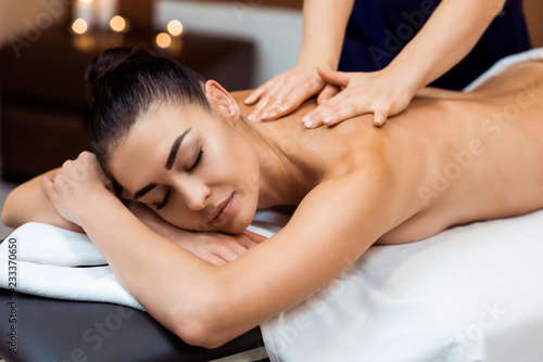 attractive young woman with closed eyes having massage therapy in spa
