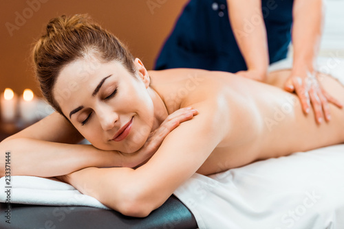 beautiful smiling girl with closed eyes enjoying massage in spa