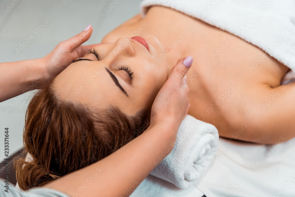 cropped shot of young woman having facial massage in spa salon