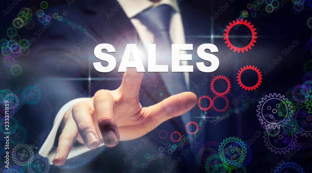 A businessman pressing a Sales business concept on a graphical display of cogs A businessman pressing a Sales business concept on a graphical display of cogs