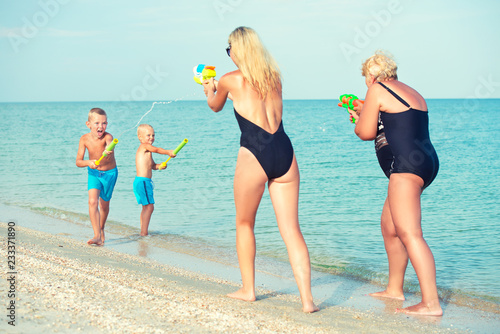 Children play with my mother and grandmother with water pistols on the beach.Summer time 