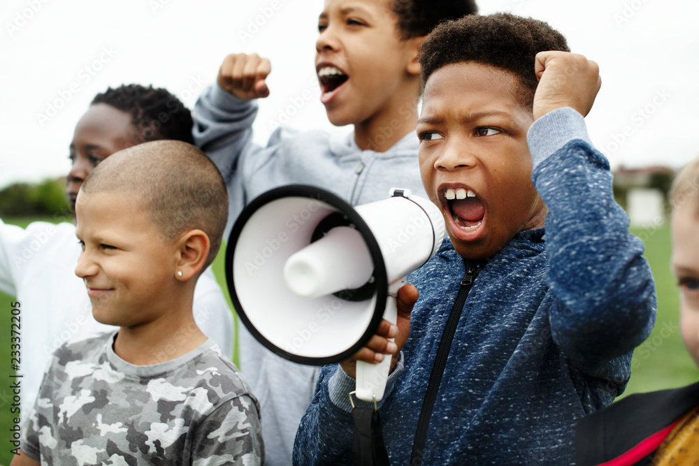 Young boy shouting on a megaphone in a protest - obrazy, fototapety, plakaty 