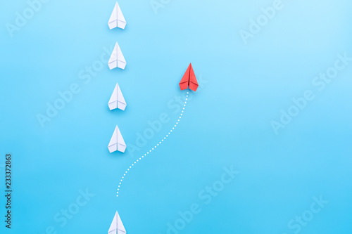 Group of white paper plane in one direction and one red paper plane pointing in different way on blue background. Business concept for new ideas, creativity, innovation and solution.