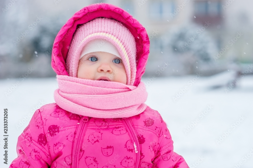 Baby in winter overalls wrapped in a scarf walks on a snow-covered street and sculpts from snow. Baby in winter overalls wrapped in a scarf walks on a snow-covered street and sculpts from snow.