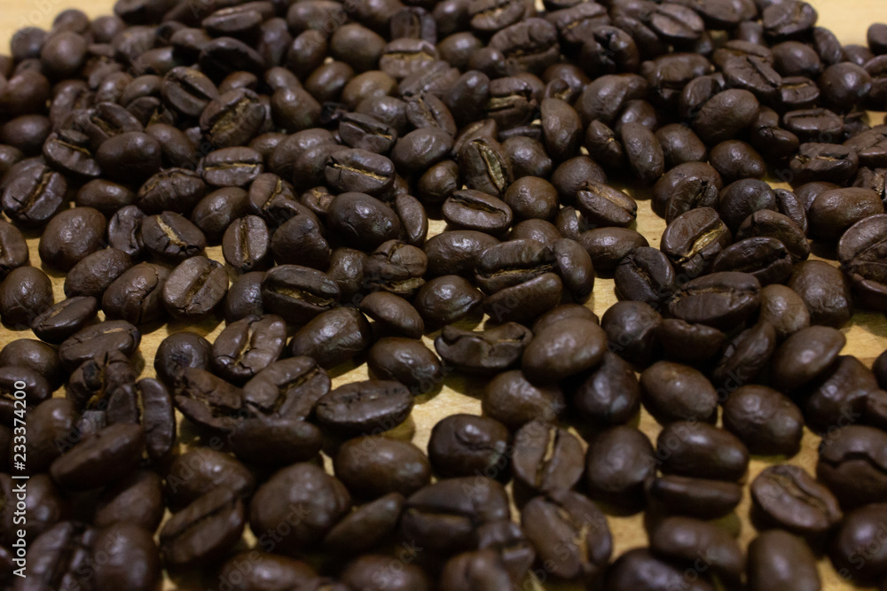 Fototapeta premium Pile of coffee bean on wooden table closeup.