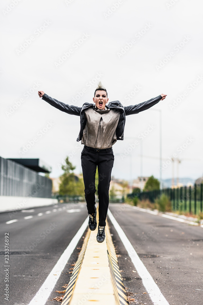 Punk woman jumping on divider at roadside Punk woman jumping on divider at roadside