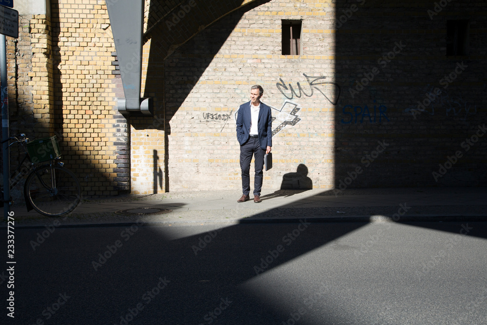 Businessman standing at graffiti wall looking around