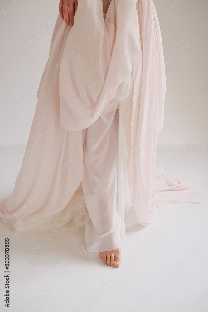 Bride in an elegant silk dress stands and holds the dress by the edge belt, White background Bride in an elegant silk dress stands and holds the dress by the edge belt, White background