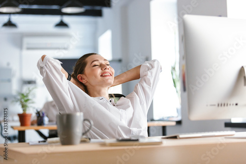 Konstfotografi Happy young woman dressed in shirt sitting at her workplace