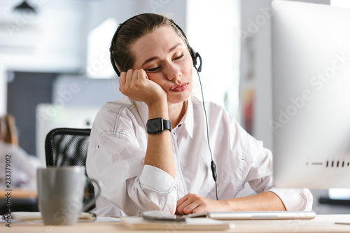 Bored young woman wearing microphone headset