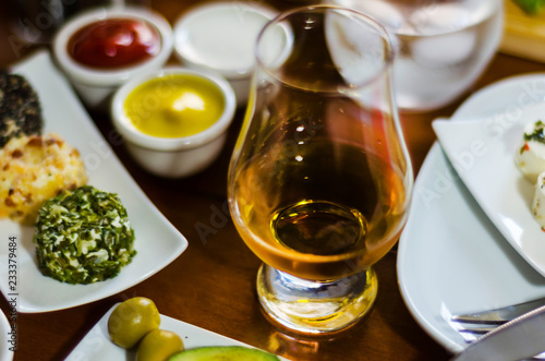 glass of whisky single malt and set with different appetizers in small portions