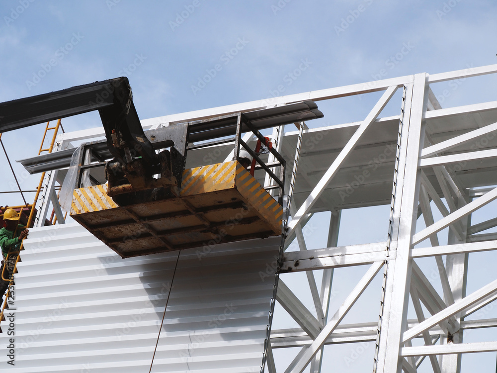 Naklejka premium Construction worker at construction site using lifting boom machinery