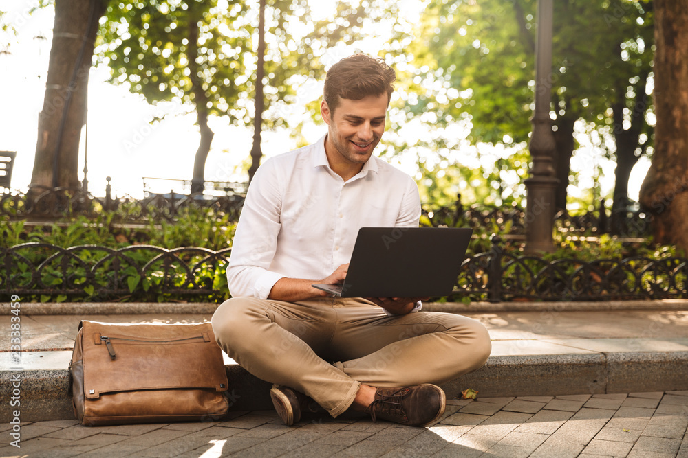 Cheerful young businessman sitting outdoors Cheerful young businessman sitting outdoors