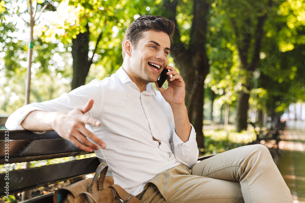 Happy young businessman sitting on a bench outdoors Happy young businessman sitting on a bench outdoors