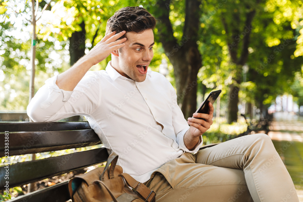 Happy young businessman sitting on a bench outdoors Happy young businessman sitting on a bench outdoors