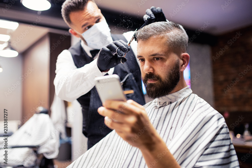 Hipster man client visiting haidresser and hairstylist in barber shop, taking selfie.