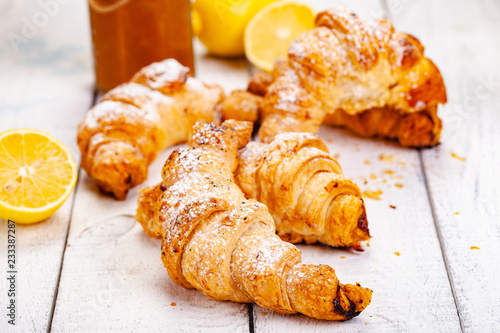 Croissants with lemon jam on white wooden background. Close up