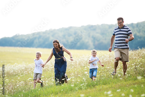 A young family with two small sons walking in nature on a summer day.