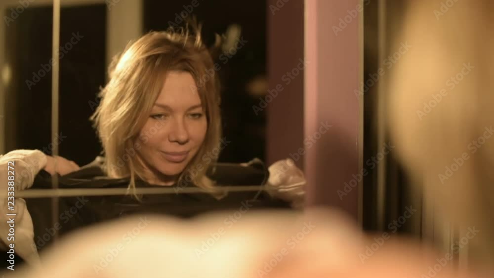Close-up of a girl magician in front of a mirror puts on the hood of his suit time after time. Live camera. Mysticism and preparation for witchcraft or carnival Close-up of a girl magician in front of a mirror puts on the hood of his suit time after time. Live camera. Mysticism and preparation for witchcraft or carnival