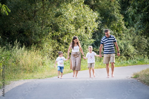 A family with two small sons walking barefoot on a road in park on a summer day. © Halfpoint
