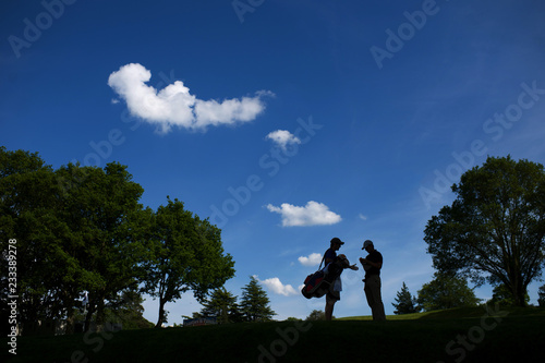 Golfer and caddy discussing tactics on a sunny day