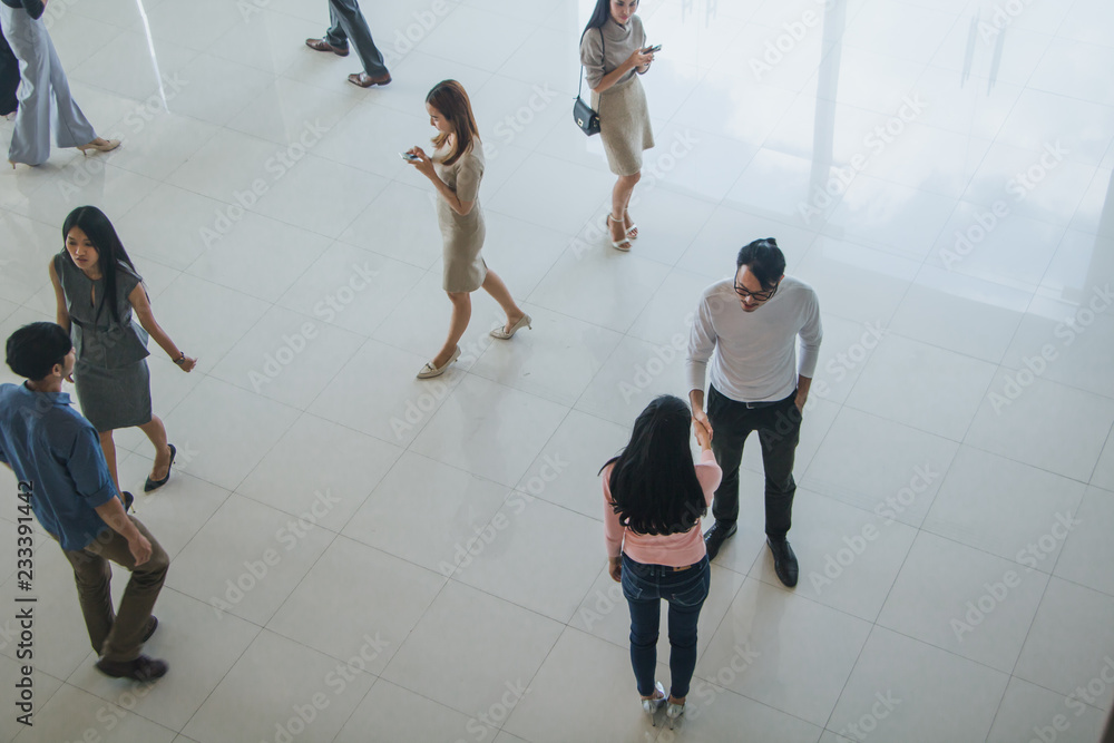 Asian office workers shake hands to greet each other in the office lobby Asian office workers shake hands to greet each other in the office lobby