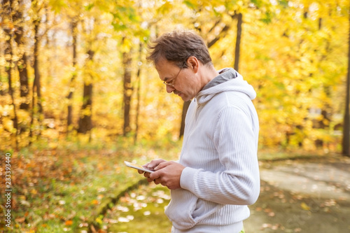 Middle-aged man, European, with a tablet in his hands in the Park.
