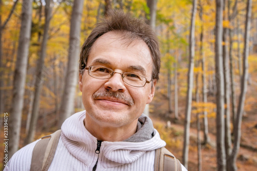 Portrait of a European man walking on a mountain trail in the autumn in the woods.