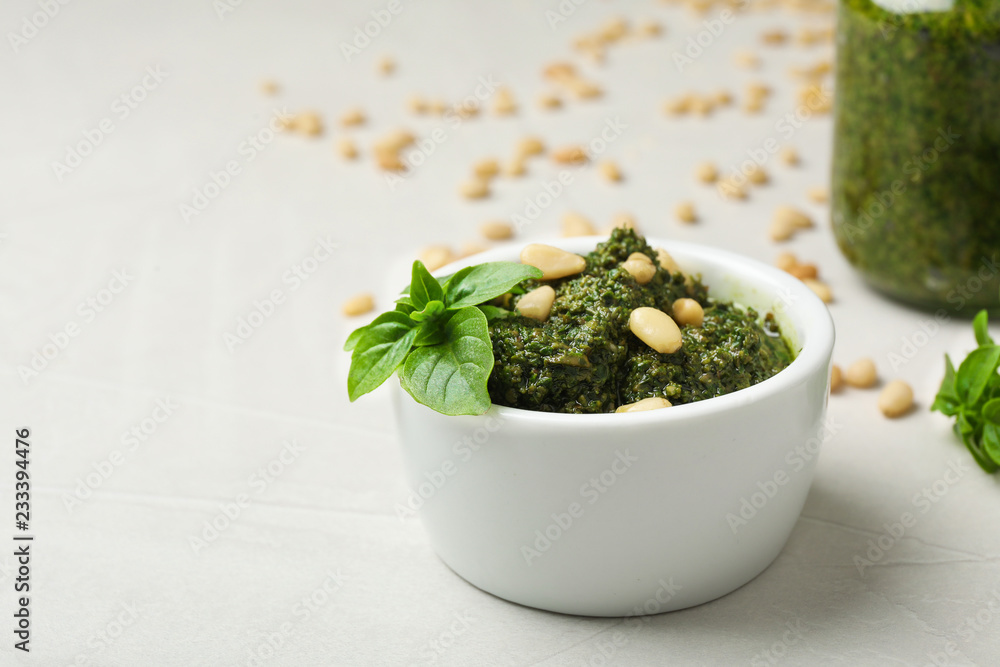 Homemade basil pesto sauce with pine tree nuts in bowl on table Homemade basil pesto sauce with pine tree nuts in bowl on table