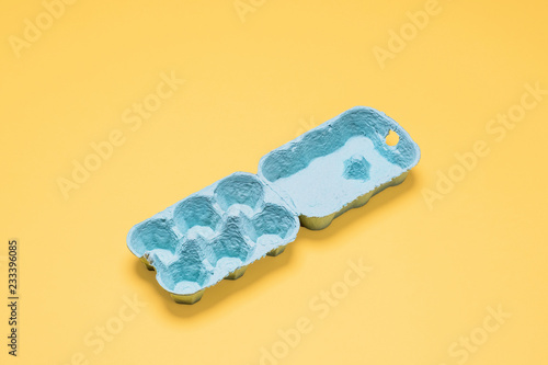Empty egg crate.  Half dozen egg carton container open on a bright pastel yellow background