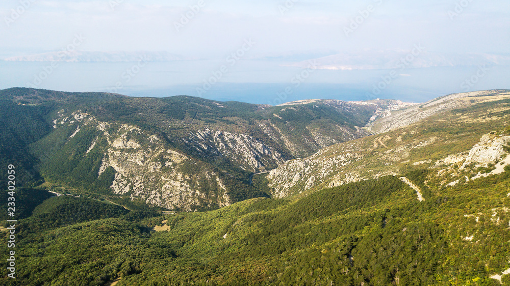 Aerial view of stone mountains with forest in Croatia and sea background