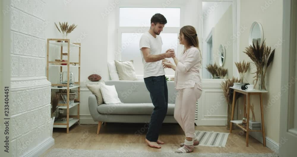 Home style couple spending a wonderfully time together in the living room dacing together , in pajamas. Home style couple spending a wonderfully time together in the living room dacing together , in pajamas.