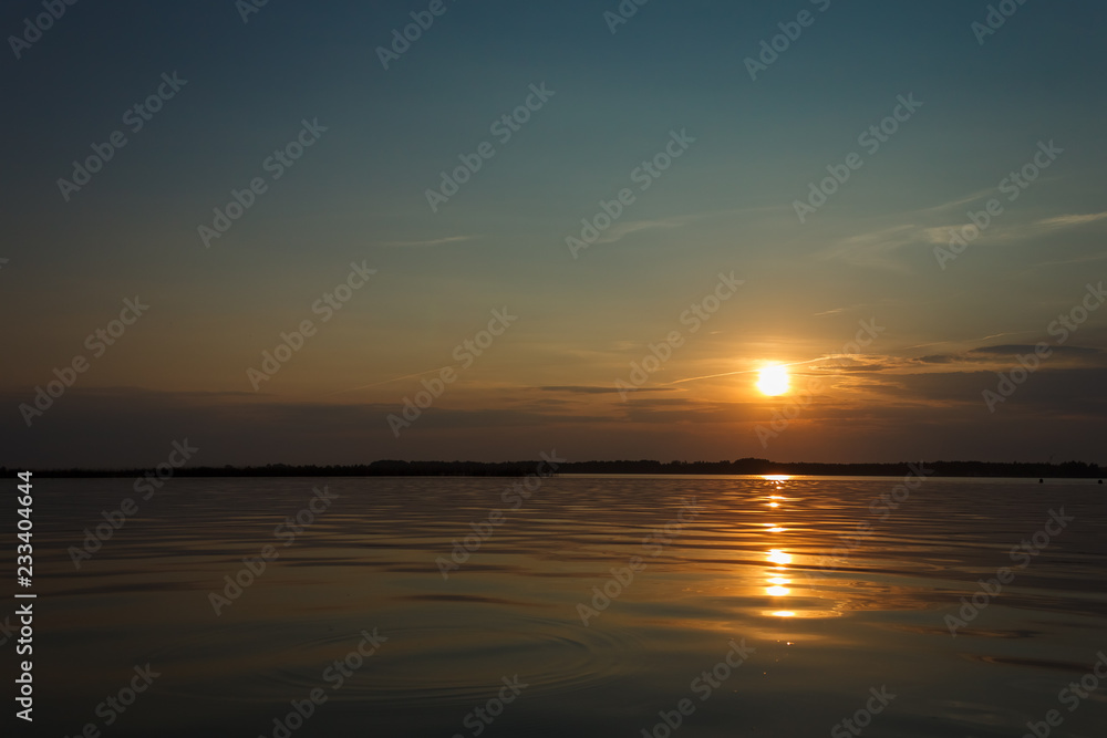 Sunset on the lake. Evening sky with beautiful clouds is reflected in the water of the lake Sunset on the lake. Evening sky with beautiful clouds is reflected in the water of the lake